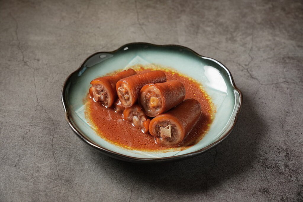 「紅麴豬尾巴」以精華上湯燉煮豬尾巴一個小時後,再以紅麴、陳皮、甘草入味,提升香氣外,還能降低豬肉的油膩感,含有豐富的膠質。(圖/神旺潮品集.忠孝店提供)