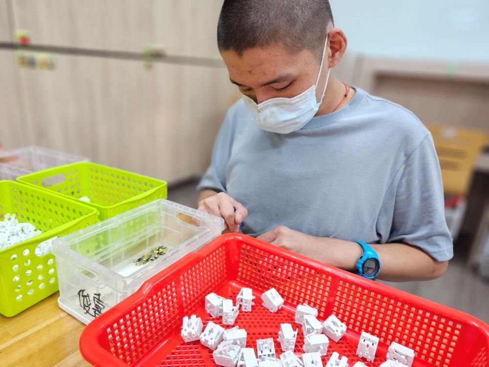 《圖說》阿嘉在新豐小作所學習組裝日光燈開關器。(社會局提供),