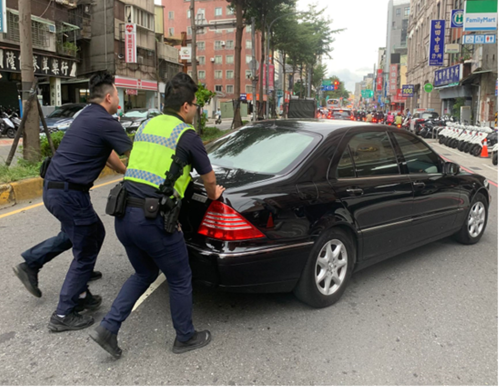 《圖說》員警顧及其它用路人安全,1人在拋錨車輛後方,疏導車輛安全通過,另2員徒手推著後車廂的方式,將故障車輛推到路旁。〈三重分局提供〉