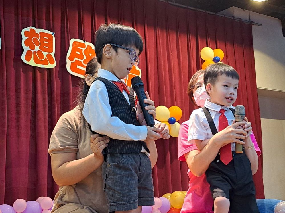 《圖說》患有水腦症的小宇(左)從坐不穩到可以上台代表致詞,感謝老師一路的照顧。〈社會局提供〉