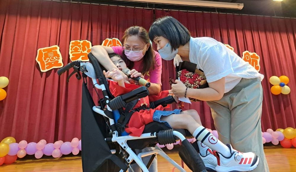 《圖說》三重日托瑞瑞的媽媽代表家長致詞後獻花給媽媽,並說媽媽我愛你,令現場來賓感動。〈社會局提供〉