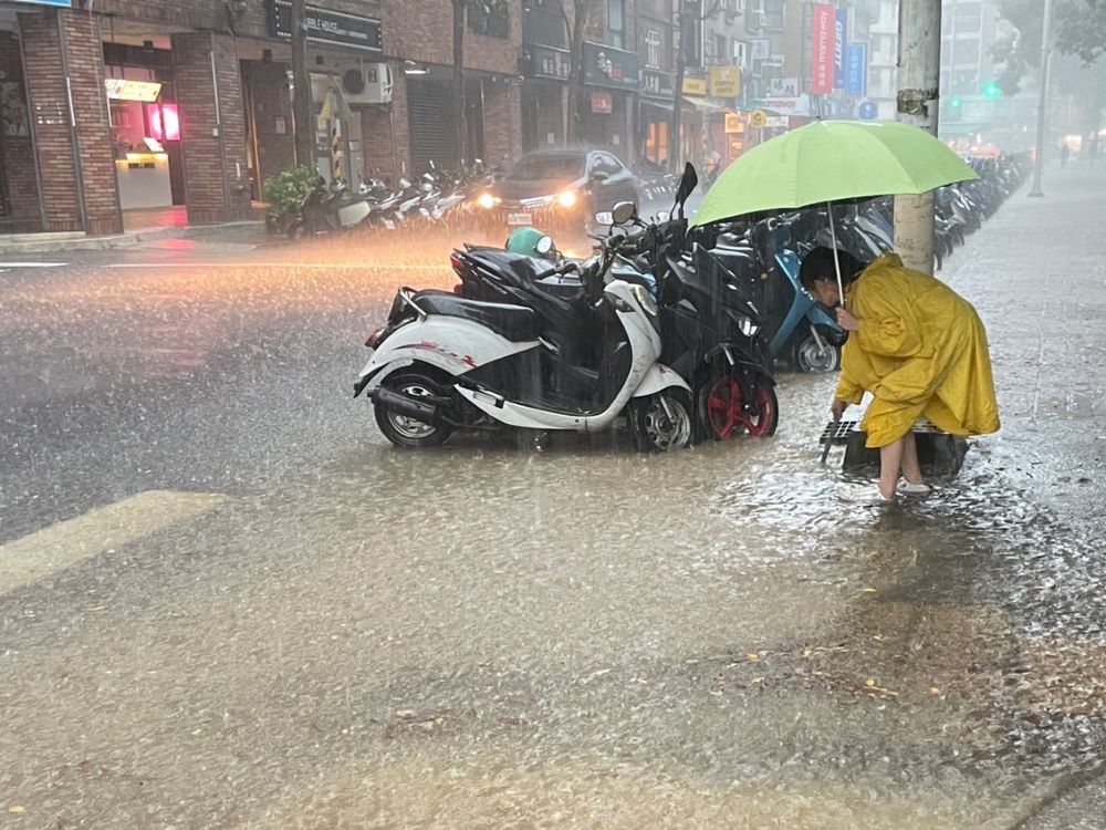 《圖說》暴雨來襲志工仍堅守任務清除垃圾落葉阻塞側溝格柵。〈水利局提供〉