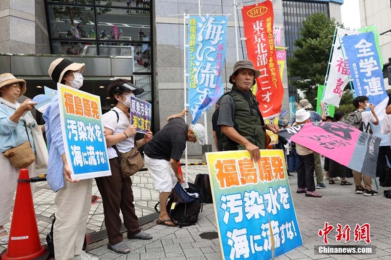 日本排放核污水當天,日本民眾在東京電力公司總部附近舉標語抗議。圖/取自中新社