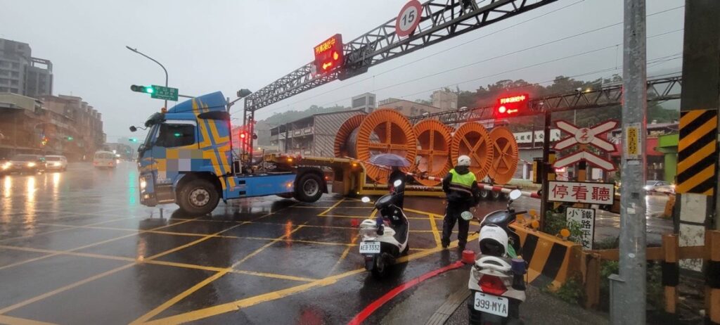 拖板車行經卡在鐵軌上,山佳派出所巡邏員警陳昱豪、黃威涵找附近推高機疾駛現場將拖板車車尾提高,讓車頭輪胎著地,車輛才順利駛離平交道