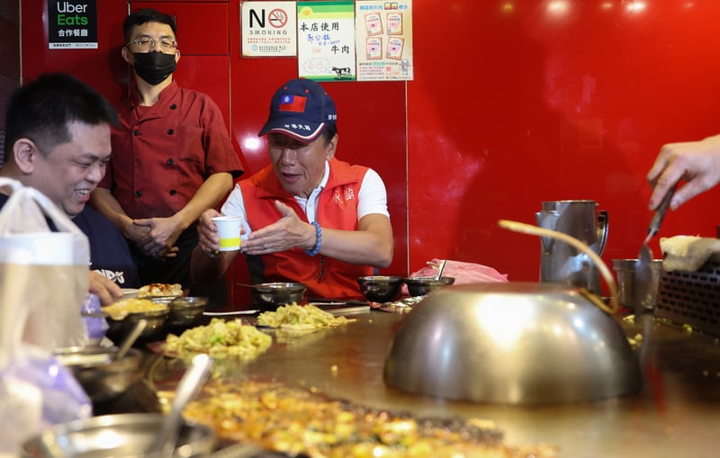 鴻海創辦人郭台銘走訪臨江夜市,在一間鐵板燒用餐,舉杯向旁邊民眾致意。中央社