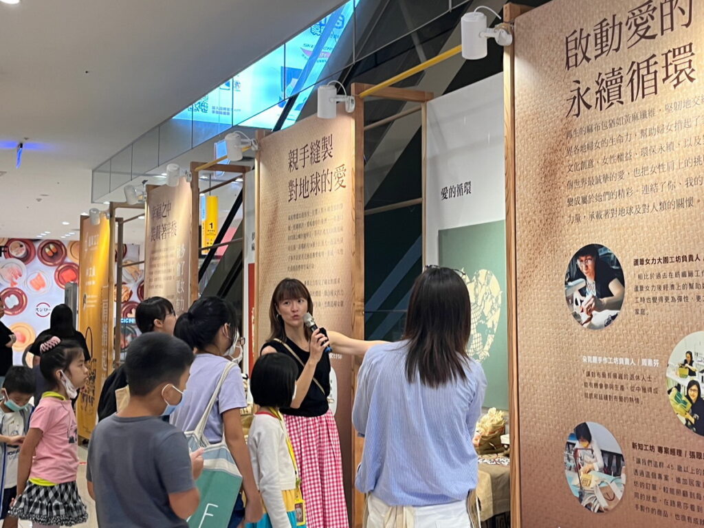 紙雕藝術家林文貞為小朋友導覽「一肩揹起的愛特展」畫作及承載著故事的咖啡麻布豆袋