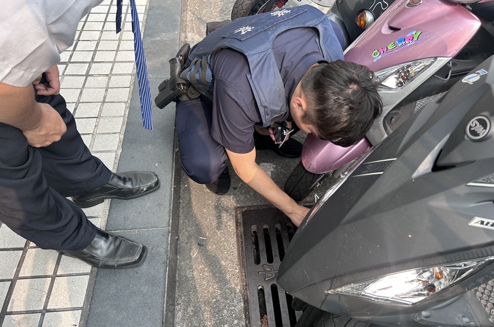 ▲圖說:西區所副所長蹲在路旁水溝蓋上,用簡易鐵鉤細心將鑰匙圈緩緩勾起 (圖/台中市政府提供)