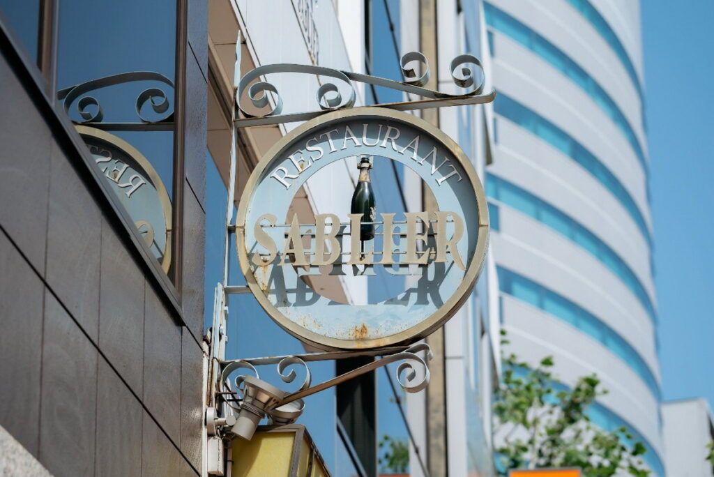 BISTRO SABLIER的招牌架著一個酒瓶，期盼顧客來店享用美味料理。（ⒸBISTROSABLIER）