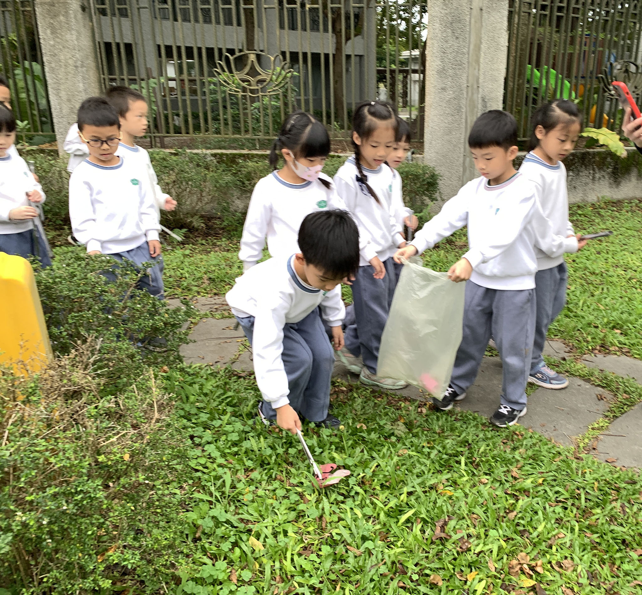幼兒園相互合作,草叢中小紙屑也不放過