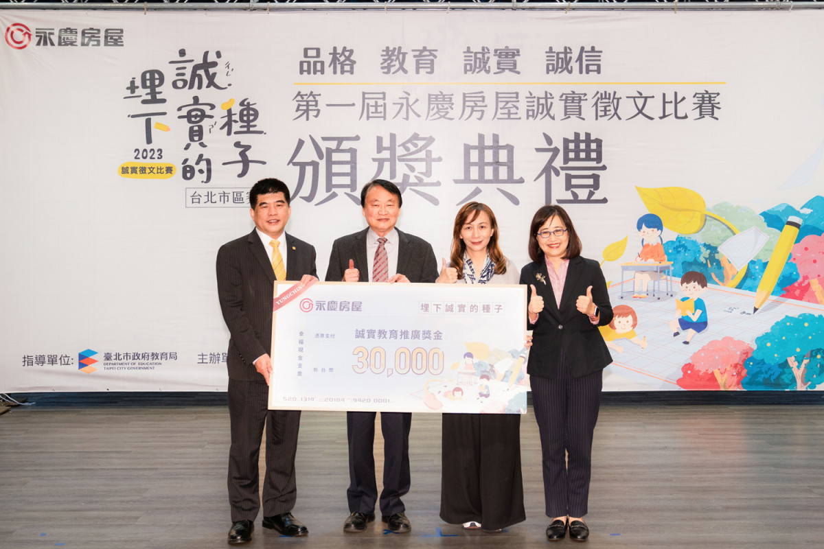 永慶房屋吳良治(左1),在林奕華副市長(右1)的見證下,頒發3萬元「誠實教育推廣獎學金」給新民小學校長饒邦安(左2)與再興小學校長楊珩(右2)。