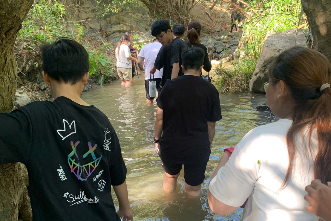 孩子不時回頭確認媽媽涉水狀況,提醒水底有石頭。