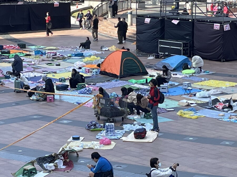 圖／歌迷為搶佔好的視野，已經提前以野餐墊在市民廣場前佔位，卻讓市民廣場彷彿貼上狗皮藥膏。（圖／記者陳志仁攝，2023.12.07）
