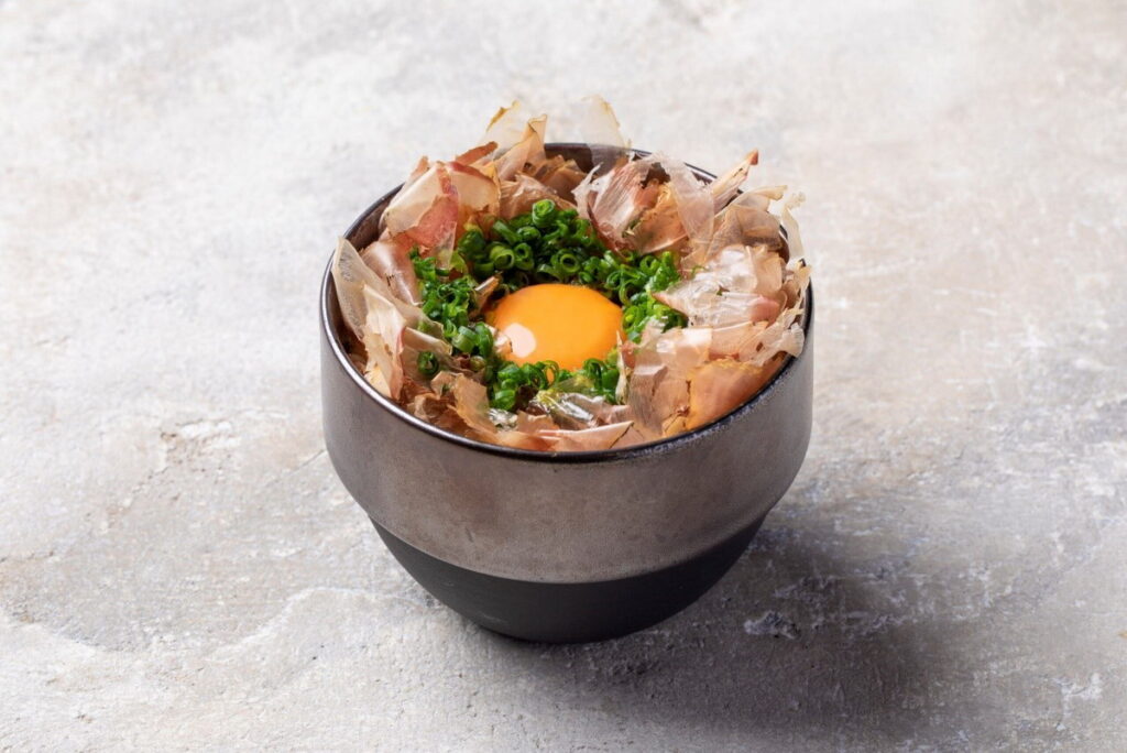 這碗熱騰騰的白米飯，舖滿著柴魚片、蔥花，加上新鮮生蛋，這樣的美味早餐，令人垂涎三尺。ⒸKatsuo Shokudo）