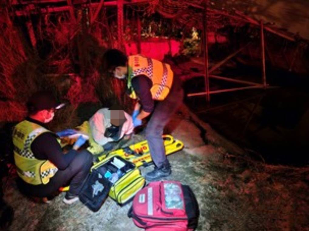龍井分駐所警員顏俊賢與消防人員合作將他抬回人行道上。(圖/記者江雁武翻攝)