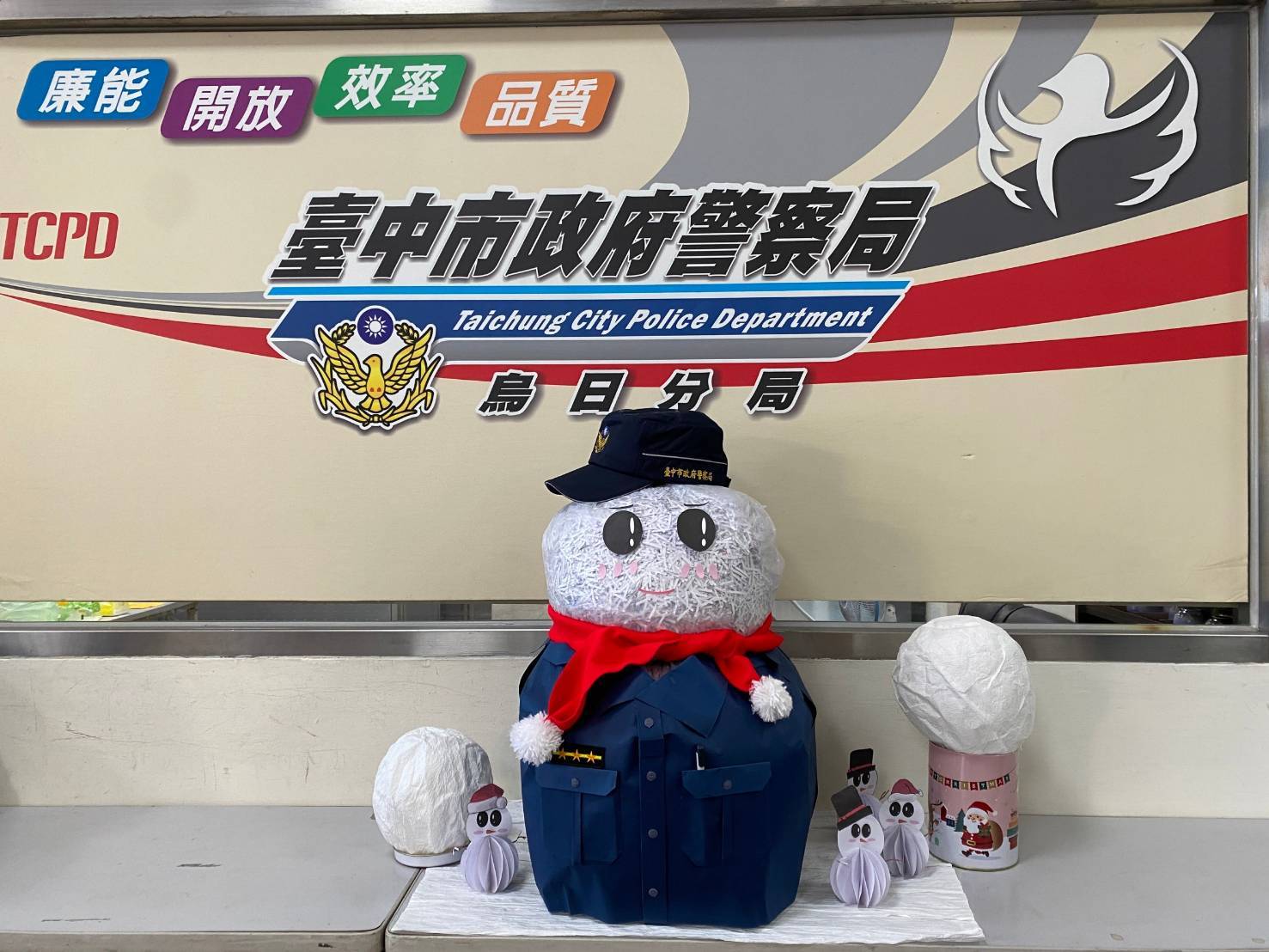 可愛的耶誕老公公是由廢棄的碎紙製成，配戴警帽、圍上紅圍巾，於烏日派出所前執勤。(圖/記者江雁武翻攝)
