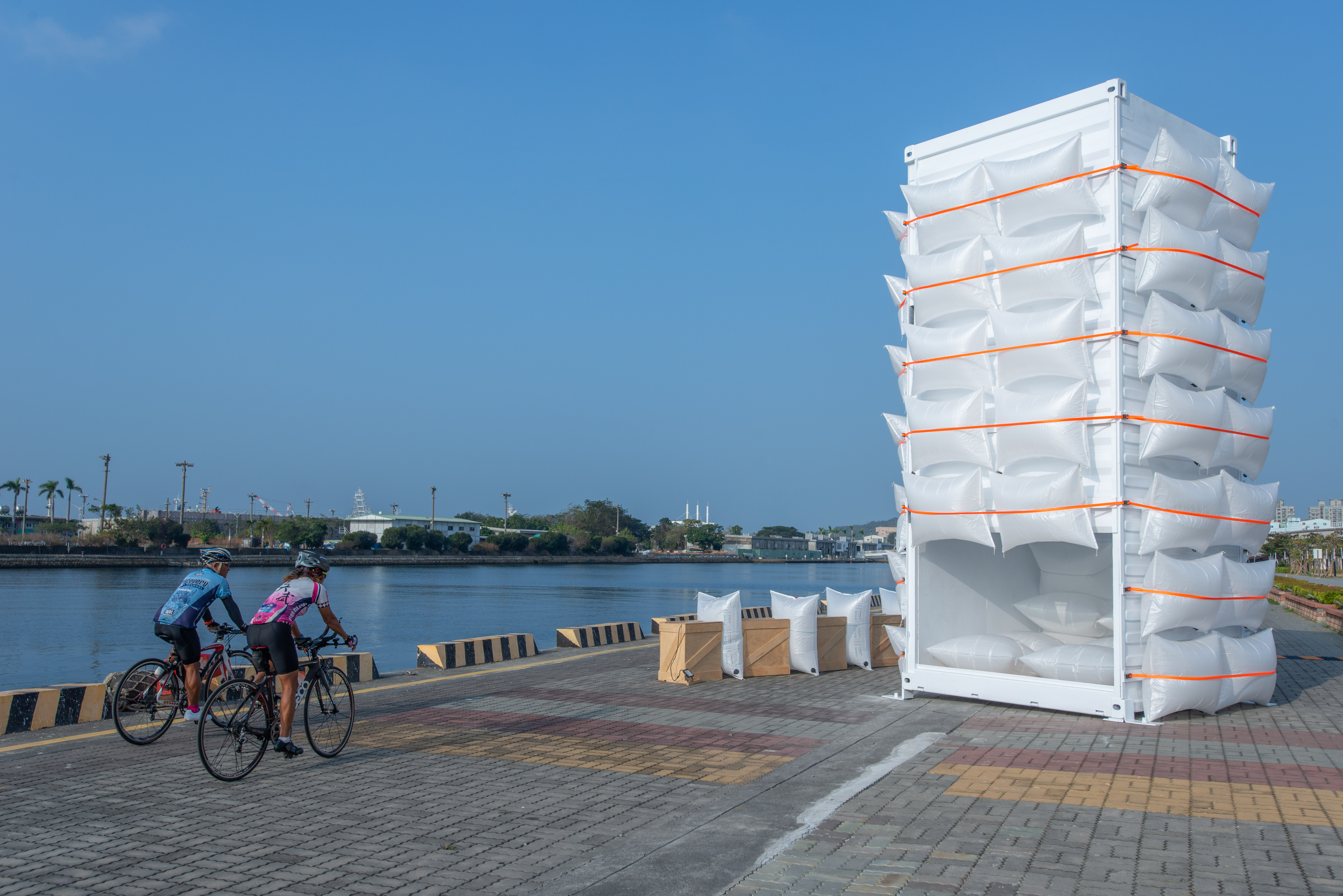 由草原市務所製作的「兩百萬克與兩百克」作品,翻轉貨櫃內與外,將貨櫃內部緩衝袋組成沙發,觀眾在互動中體會緩衝袋在海運過程時,輕盈耐撞的重要性。 (圖片提供/高美館 攝影)