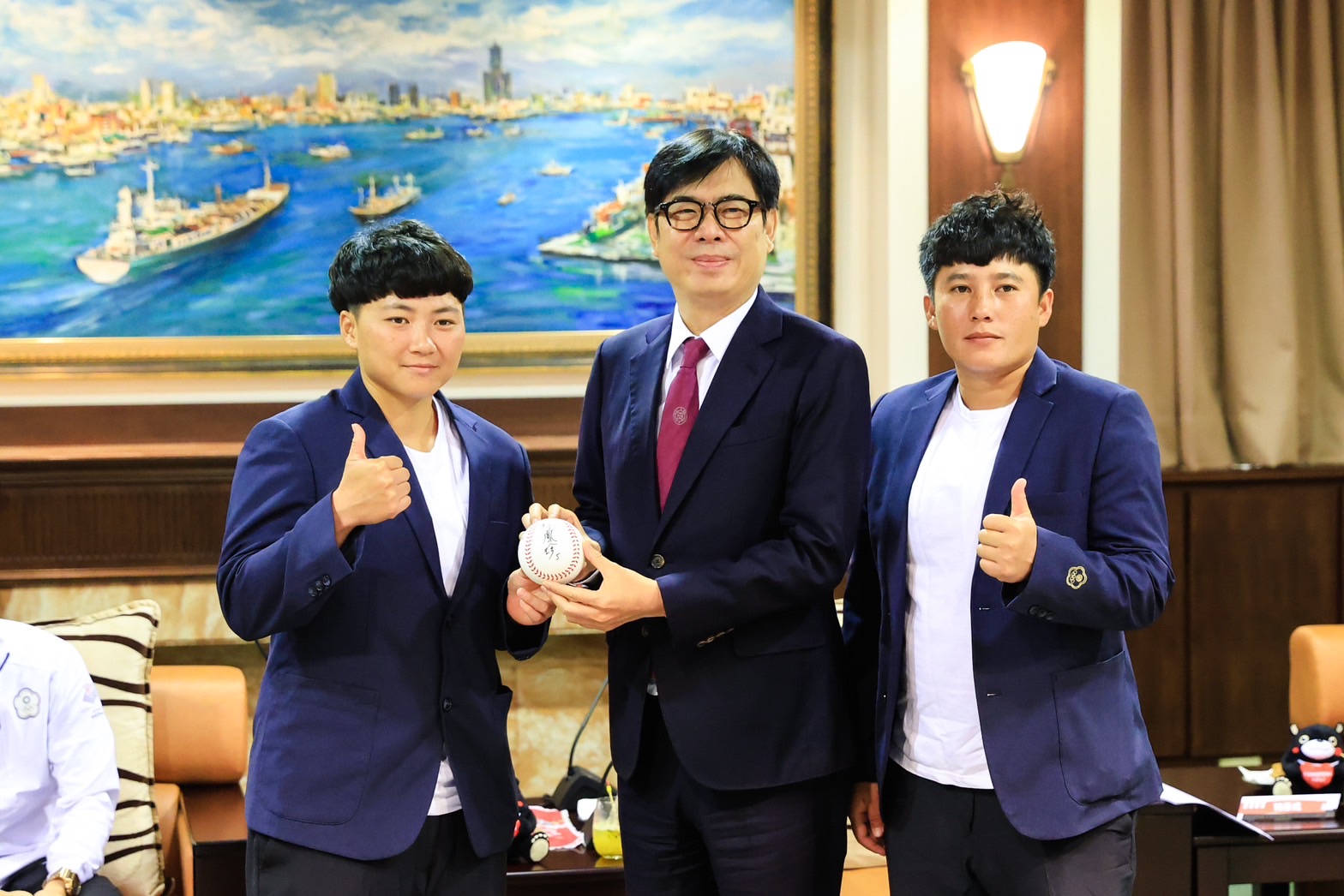 亞運銅牌壘球選手林鳳珍(左1)與蘇奕璇(右1)共同獻上簽名球給高雄市長陳其邁。(新聞局提供)