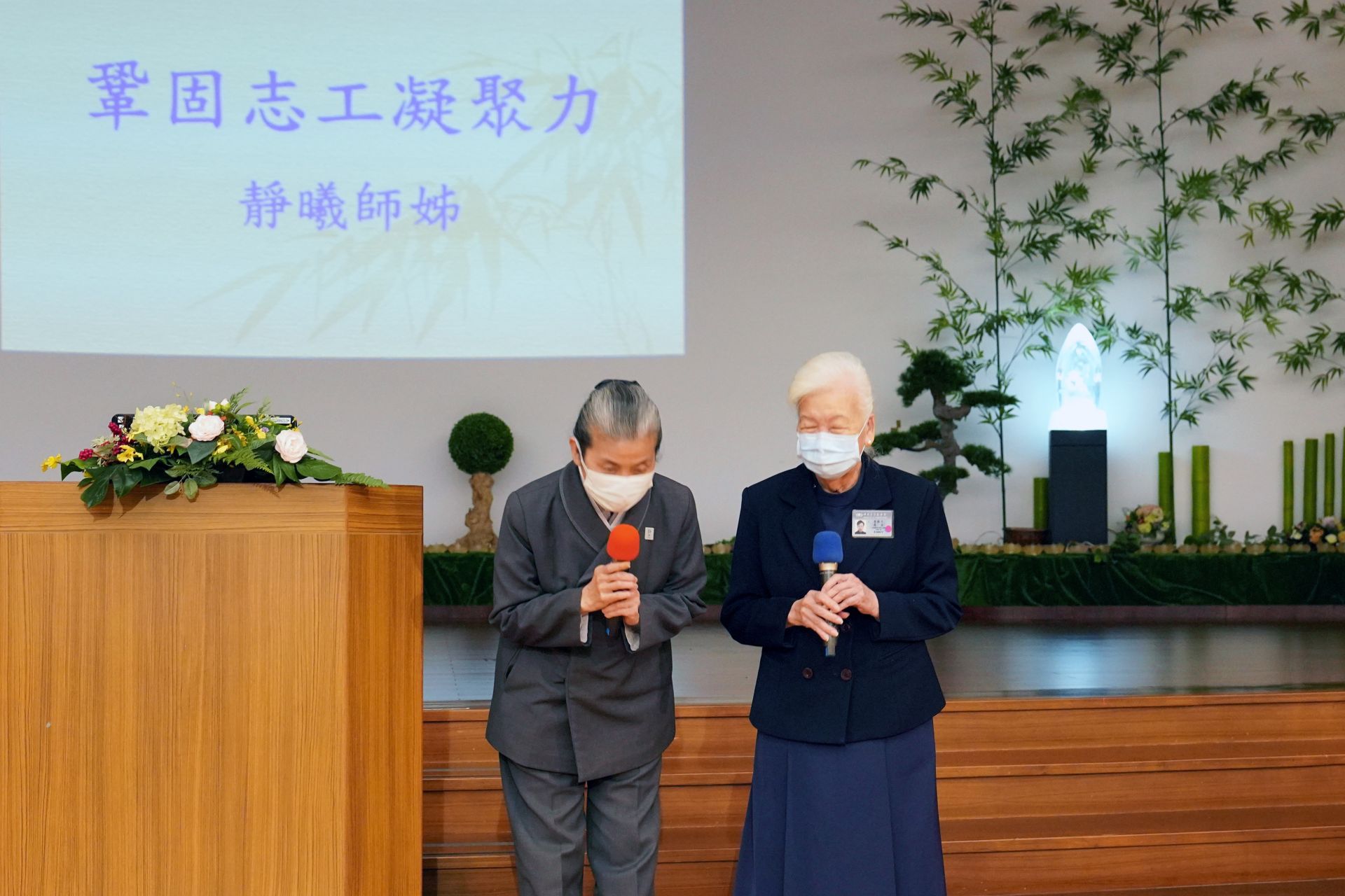 顏靜曦師姊(左)跟李節子師姊一走到台前就深深一鞠躬,感恩醫療志工全年無休付出。<br/>李節子師姊(右)叮嚀,做領隊最重要訣竅就是「不能給人家看臉色」。