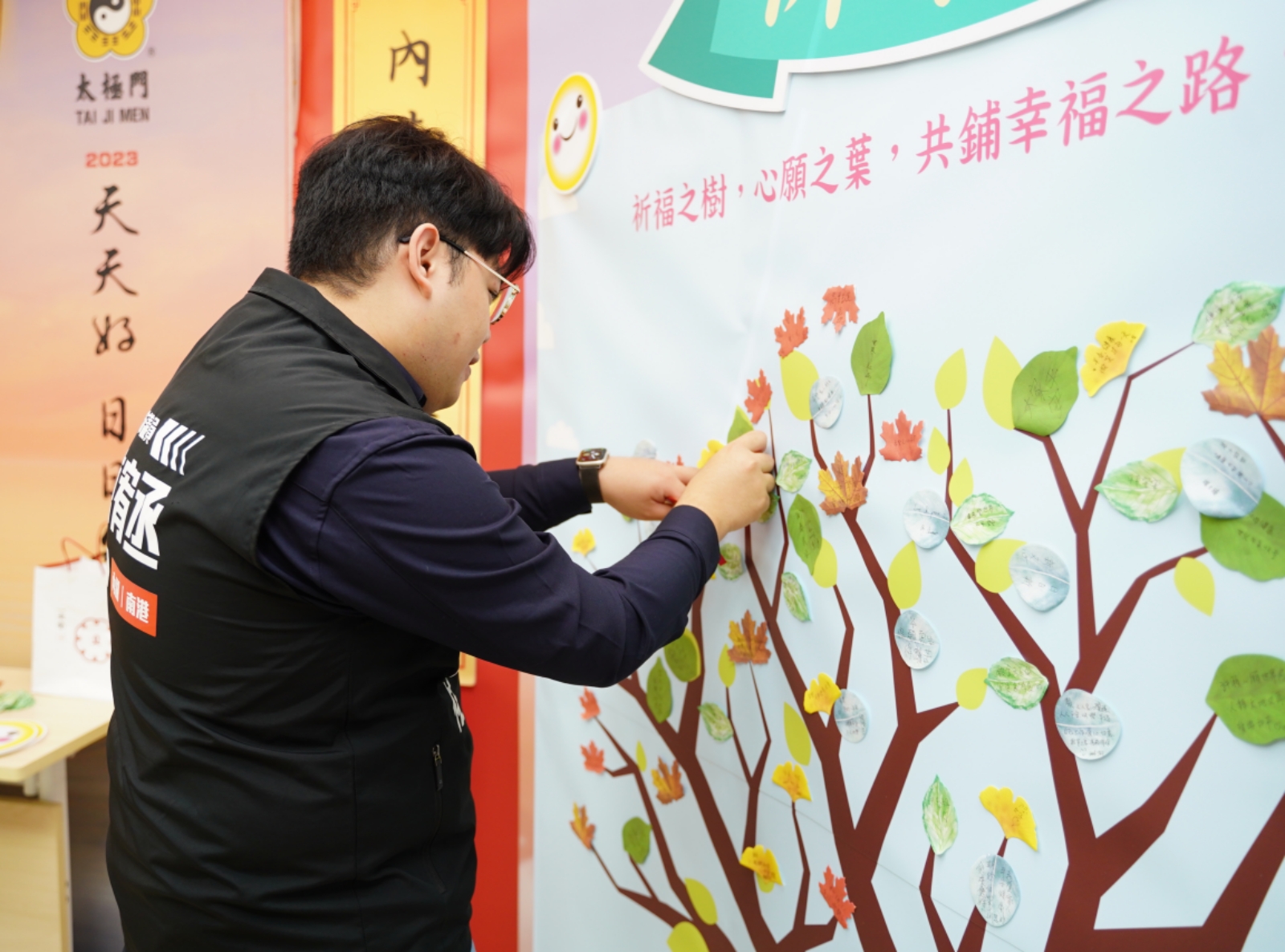 ▲臺北市議員陳宥丞服務處主任羅陳政佑將心願卡之葉貼在祈福之樹上，為2024年獻上滿滿祝福。（記者李欣翻攝）
