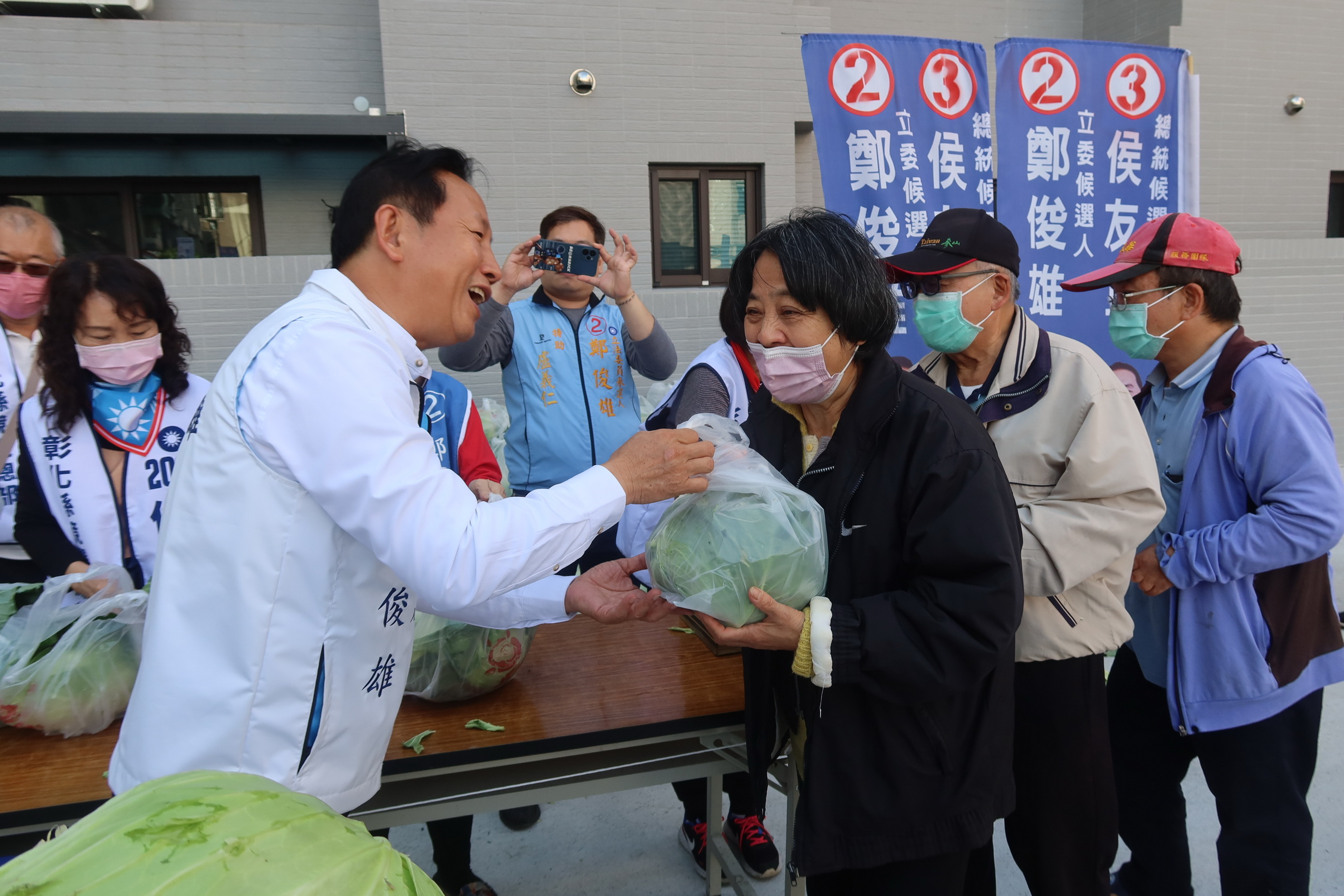 ▲彰化第四選區立委候選人鄭俊雄在競選總部發起「送菜迎侯康‧民生有靠山」活動，吸引許多民眾拿著發票排隊換高麗菜。（記者張溎壕攝）