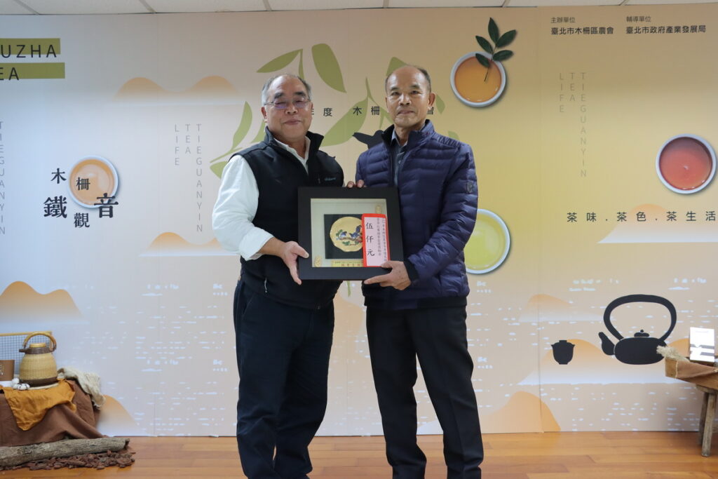 臺北市政府產業發展局劉永修簡任技正與冬茶頭等一獎得主張琮紳茶農合影。