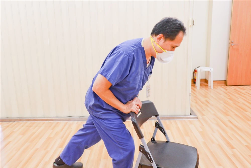 莊浩凌醫師示範自己一人的哈姆立克法,找到穩固桌椅,頂住肚臍與劍突的中間處用力推擠。