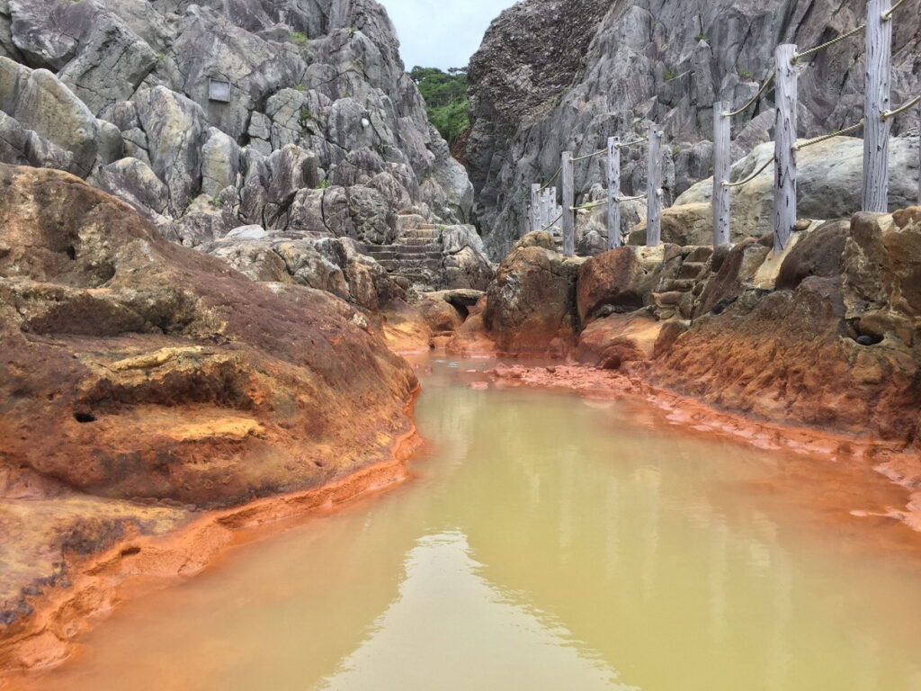 式根島「地鉈溫泉」是溫泉水流入海岸岩地所形成的潮池,退潮時溫度極高,要等到漲潮時混入海水才適合入浴。(©TCVB)