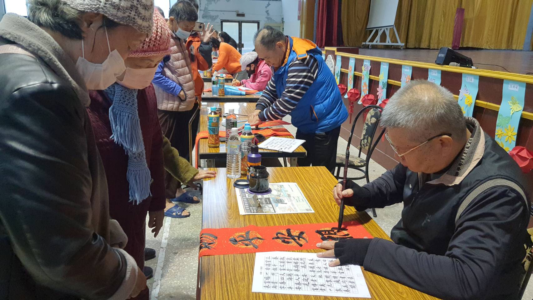 ▲彰化榮家辦理「龍送吉祥迎甲辰－春聯揮毫賀新春」活動，邀請書法名家現場揮毫，吸引住民和職員工大排長龍索取，把有溫度的春聯帶回家。（記者張溎壕攝）