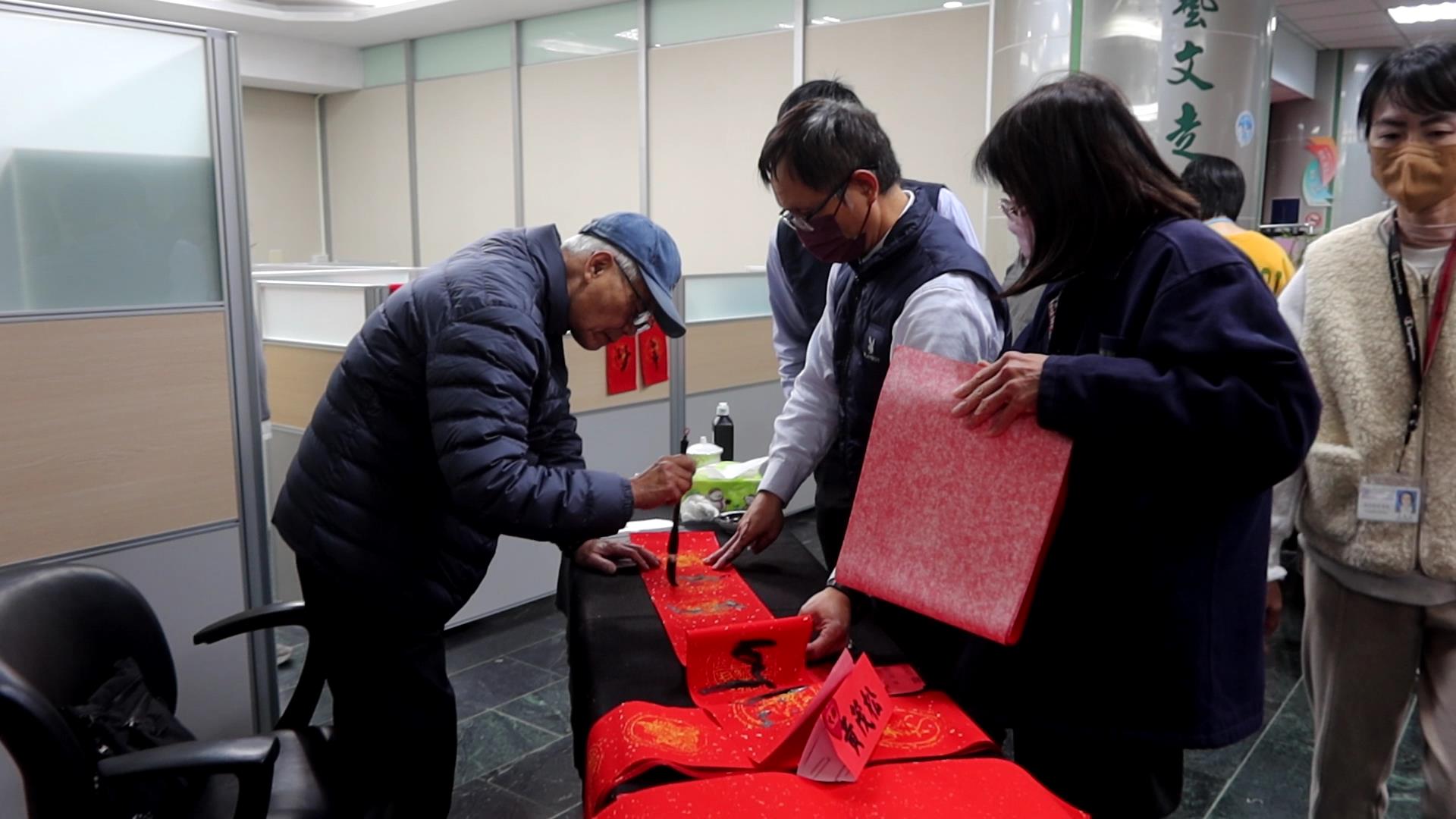 ▲台電彰化區營業處舉辦「好運龍來名家揮毫贈春聯」活動，12位書畫名家現場揮毫，為民眾打造獨一無二的吉祥春聯，吸引眾多鄉親排隊索取熱騰騰的現寫春聯。（記者張溎壕攝）