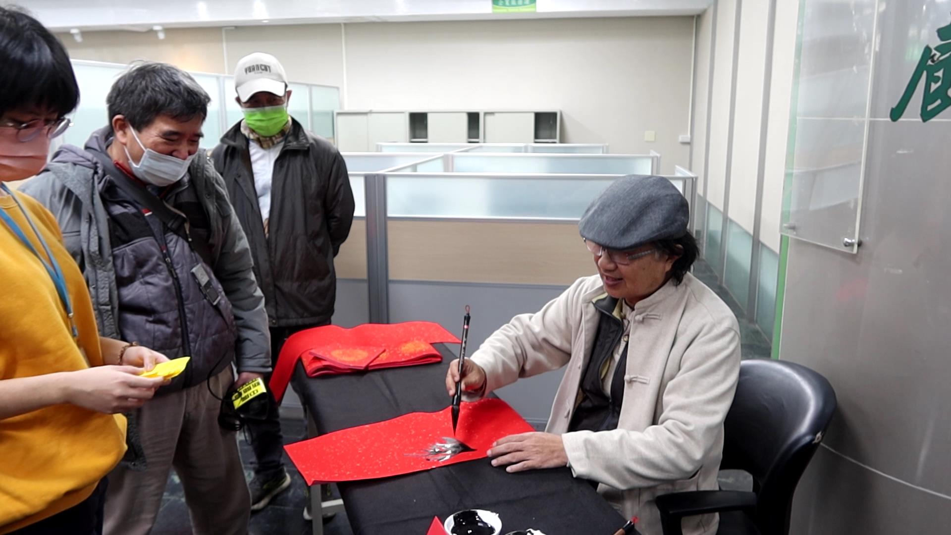 ▲台電彰化區營業處舉辦「好運龍來名家揮毫贈春聯」活動，12位書畫名家現場揮毫，為民眾打造獨一無二的吉祥春聯，吸引眾多鄉親排隊索取熱騰騰的現寫春聯。（記者張溎壕攝）