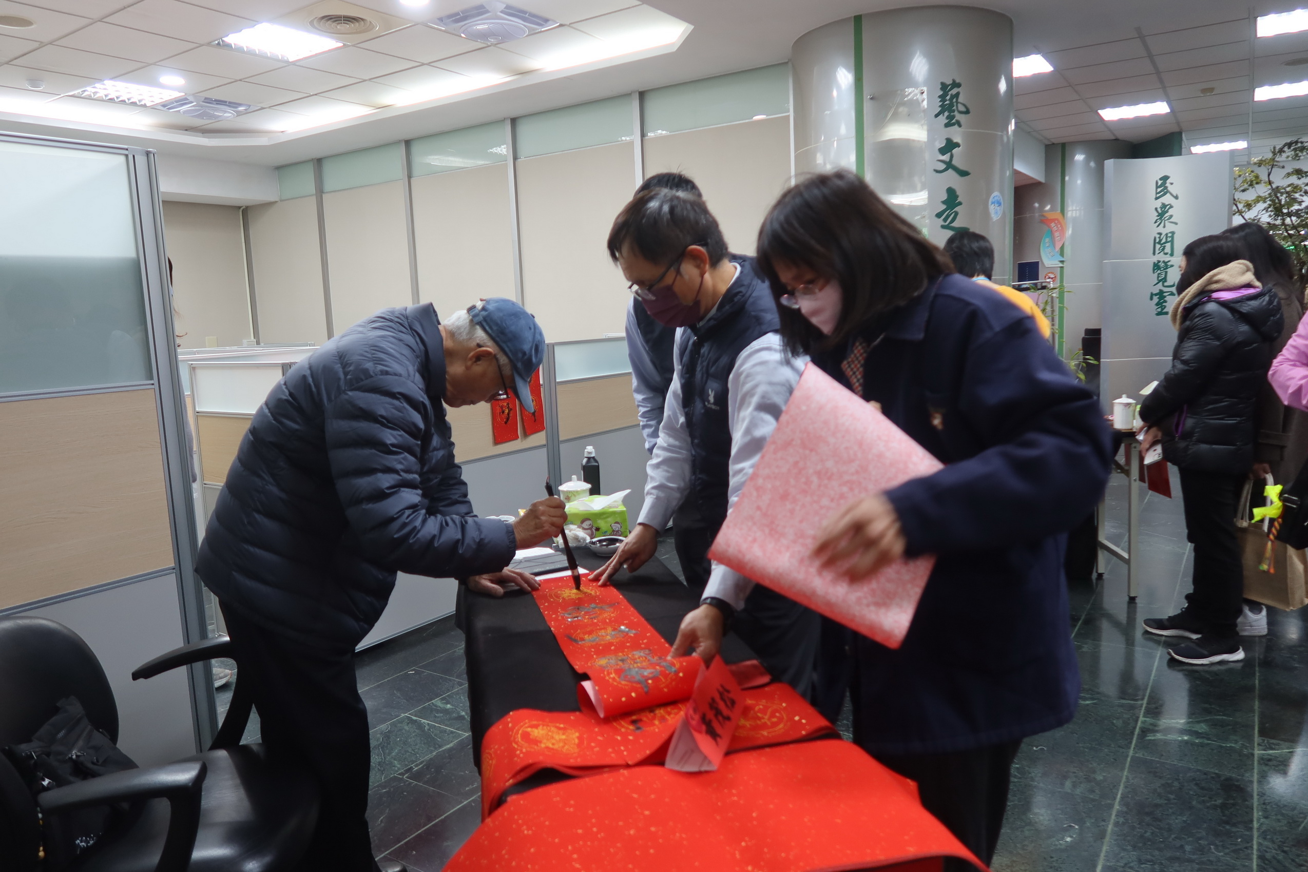 ▲台電彰化區營業處舉辦「好運龍來名家揮毫贈春聯」活動，12位書畫名家現場揮毫，為民眾打造獨一無二的吉祥春聯，吸引眾多鄉親排隊索取熱騰騰的現寫春聯。（記者張溎壕攝）