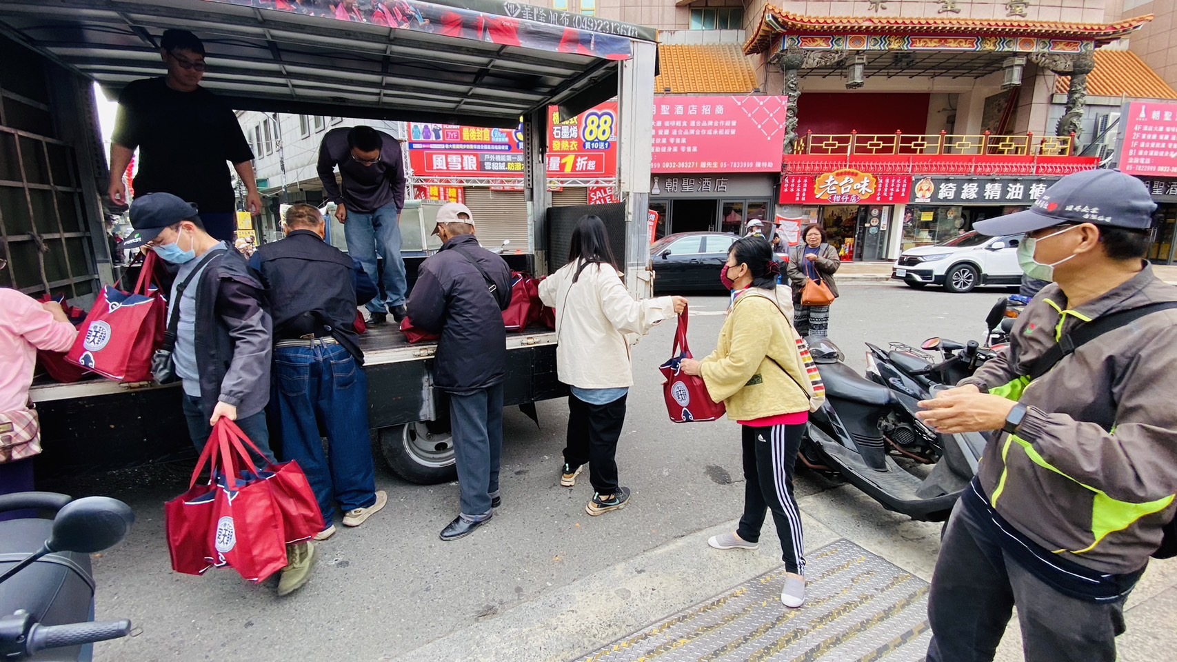 ▲透過人龍接力，將卡車上滿滿的物資傳遞到廟埕給予弱勢民眾。(記者陳雅琪攝)