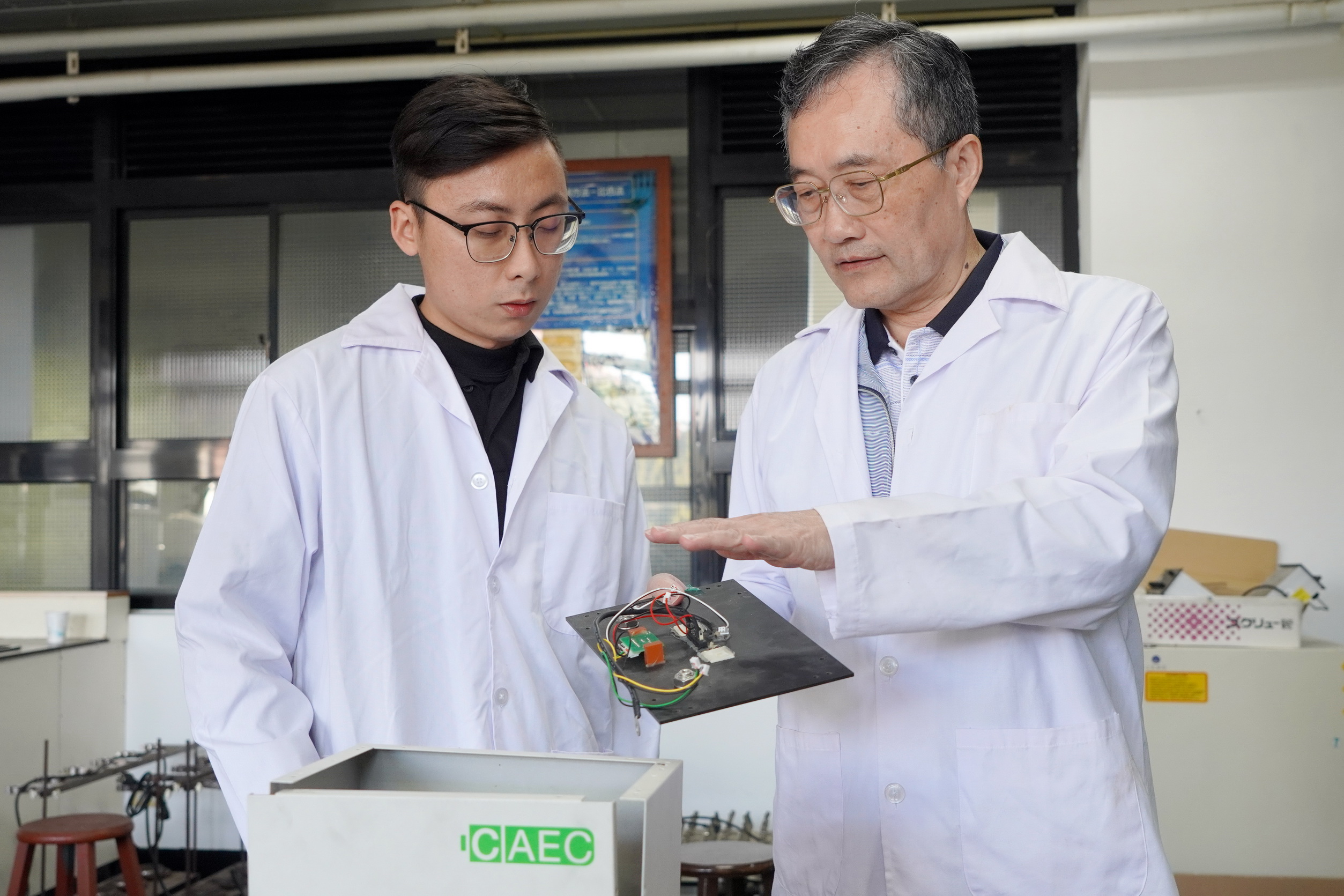 ▲大葉大學工學院李清華院長(右)與學生討論不斷電電源供應器的回收。（記者張溎壕攝）