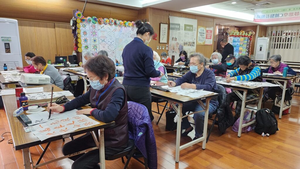 照服員翠珍介紹書法課老師陳財源是來自大甲的慈濟志工。(圖/陳惠玲攝影)