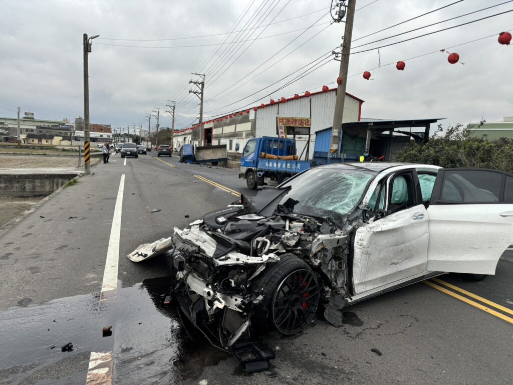 一位男子開賓士車，行經台中市大甲區興安路時，疑似超車，撞上停在路邊貨車後，再失控撞貨櫃屋，造成賓士車頭全毀，駕駛受傷送醫。(畫面翻攝)