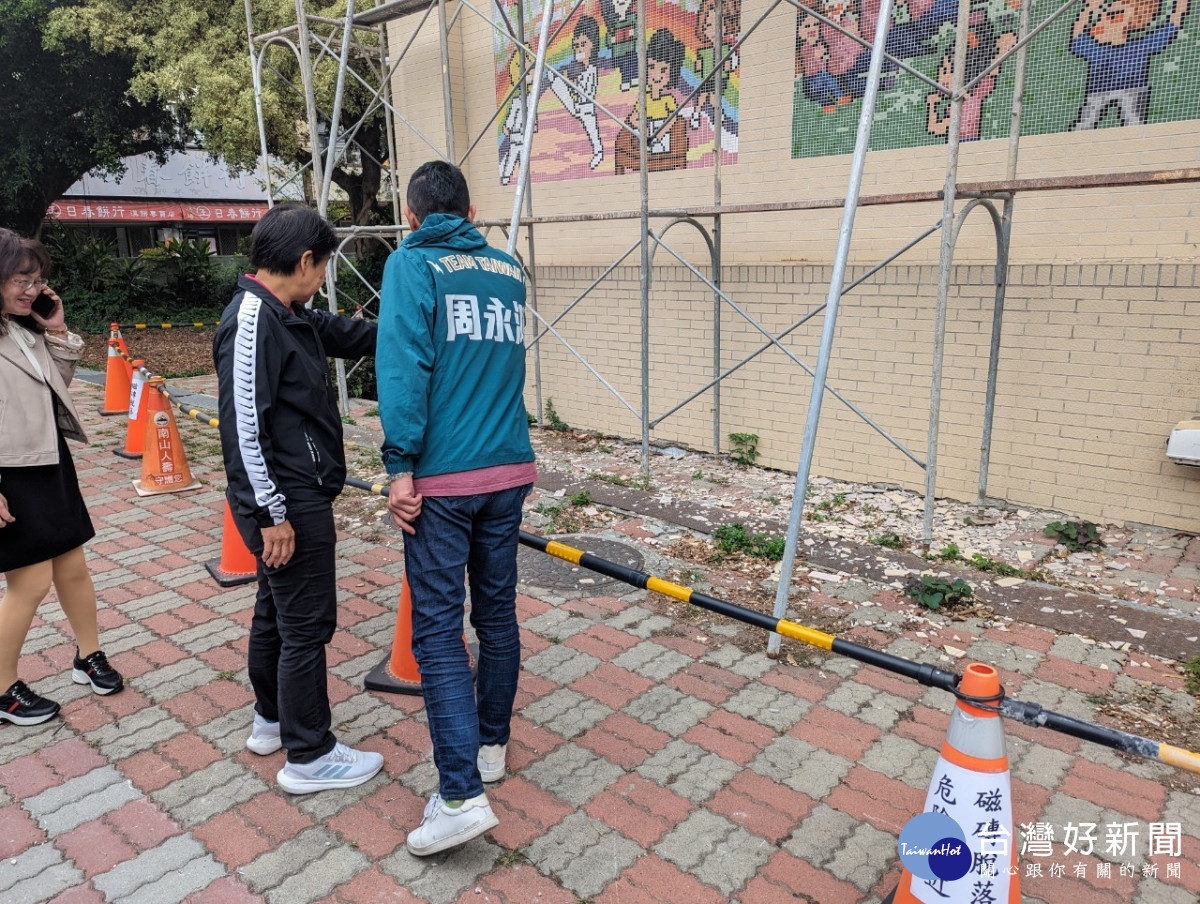 台中市議員周永鴻與圳堵里里長鄭秀燕（左）檢視磁磚剝落情形。