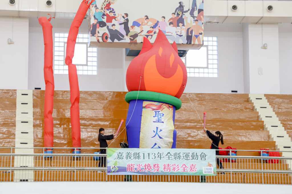 ▲梅山國中王彤綺選手與太保國中林芳琪選手分持火炬進場，登上聖火台點燃聖火，為113全縣運動會揭開序幕。（嘉義縣政府提供）