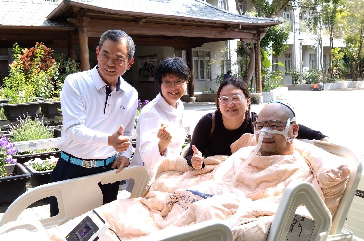 台中慈濟醫院心蓮病房護理長黃美玲(左二)、醫療志工(左一)陪伴黃鼎承(右一)與黃太太(右二)到病房外吸收陽光的滋潤。