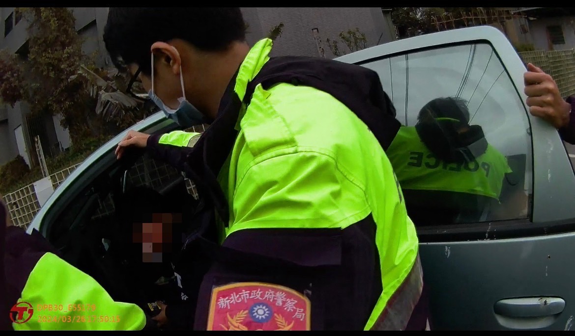 山佳派出所警員黃柏傑、黃柏翔將輕生者解救出車外畫面。(記者 張艷君翻攝)
