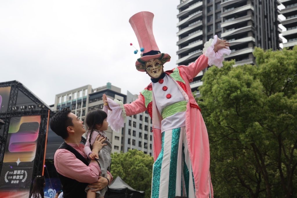 踩高蹻尋夢巨人彎身擊掌,鄭朝方市長帶動歡樂。(圖/記者黃溎芬翻攝)