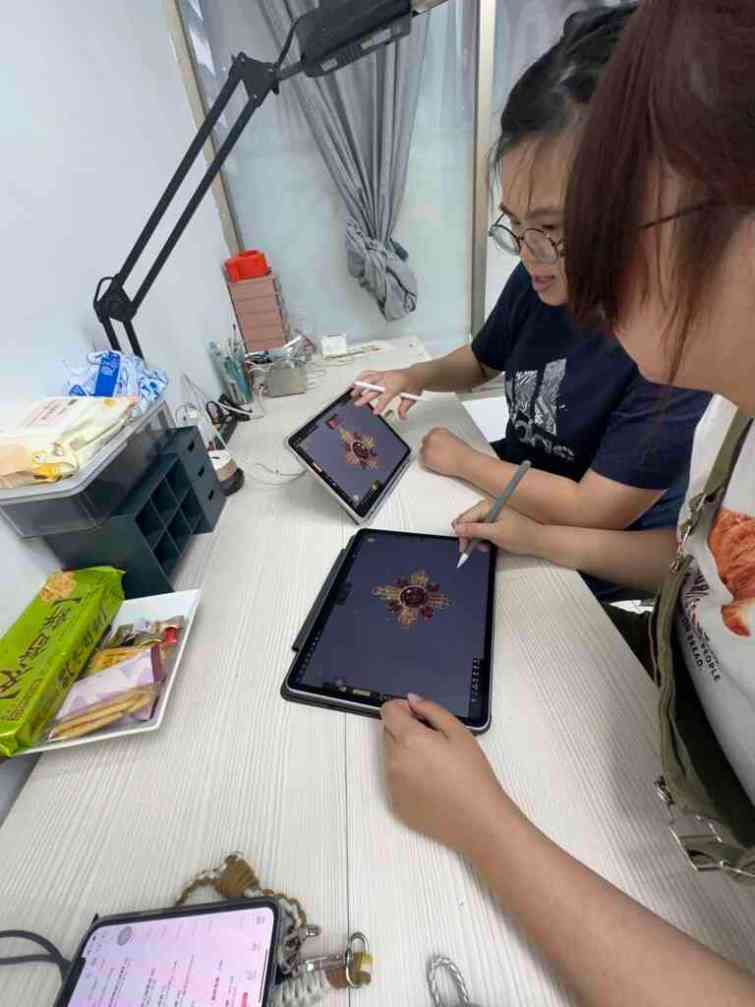 ▲謝采玲（藍衣者）於中分署結訓後成為珠寶設計工作室電腦3D繪圖講師，圖為采玲指導學員運用平板進行珠寶設計。（中彰投分署提供）