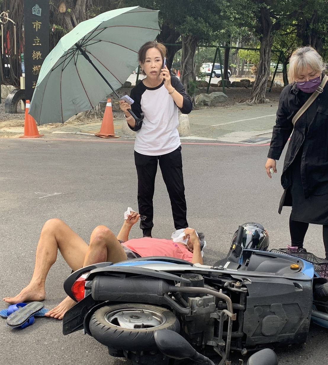 ▲台南市南區體育路橄欖球場前,上午發生一起機車車禍事故,台南市議員林美燕正巧路過該處,為傷者撐傘遮住炎炎烈日。(圖/記者陳彥霖翻攝)