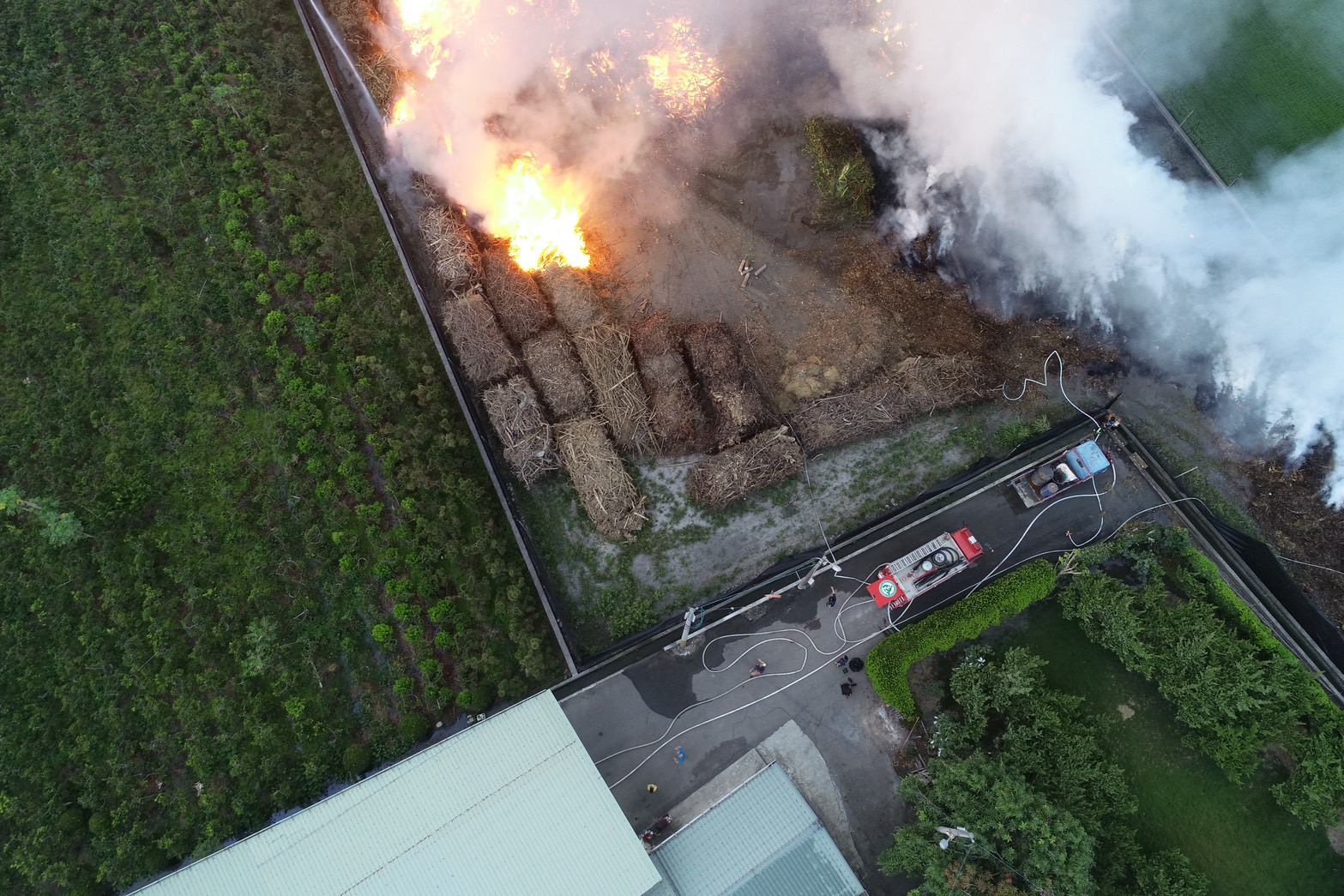 ▲田中鎮三民里一處廢棄樹枝堆置場傳出火警，消防人員利用多條水線和砲塔射水，以防止火勢再次燃燒。（消防局提供）
