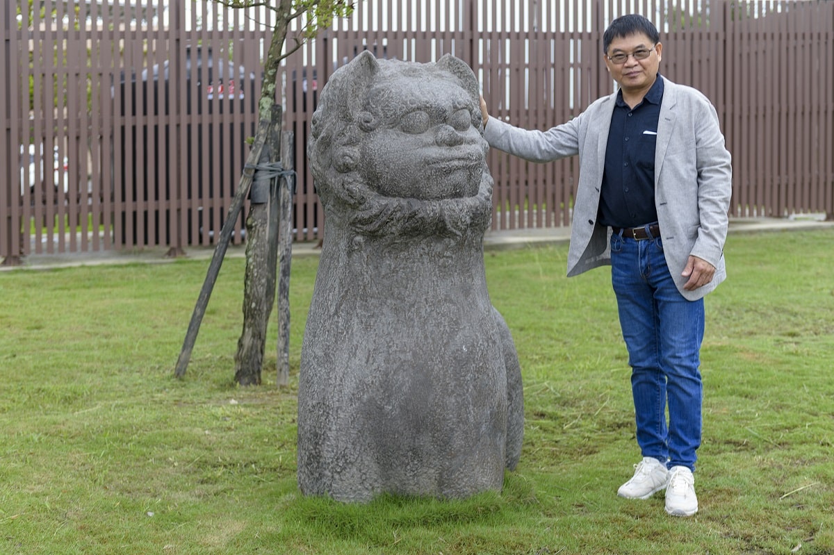 ▲台灣雕塑學會理事長／資深雕塑藝術家吳德和與園區內展示的個人雕塑石獅子作品合影。（記者劉秋菊拍攝）