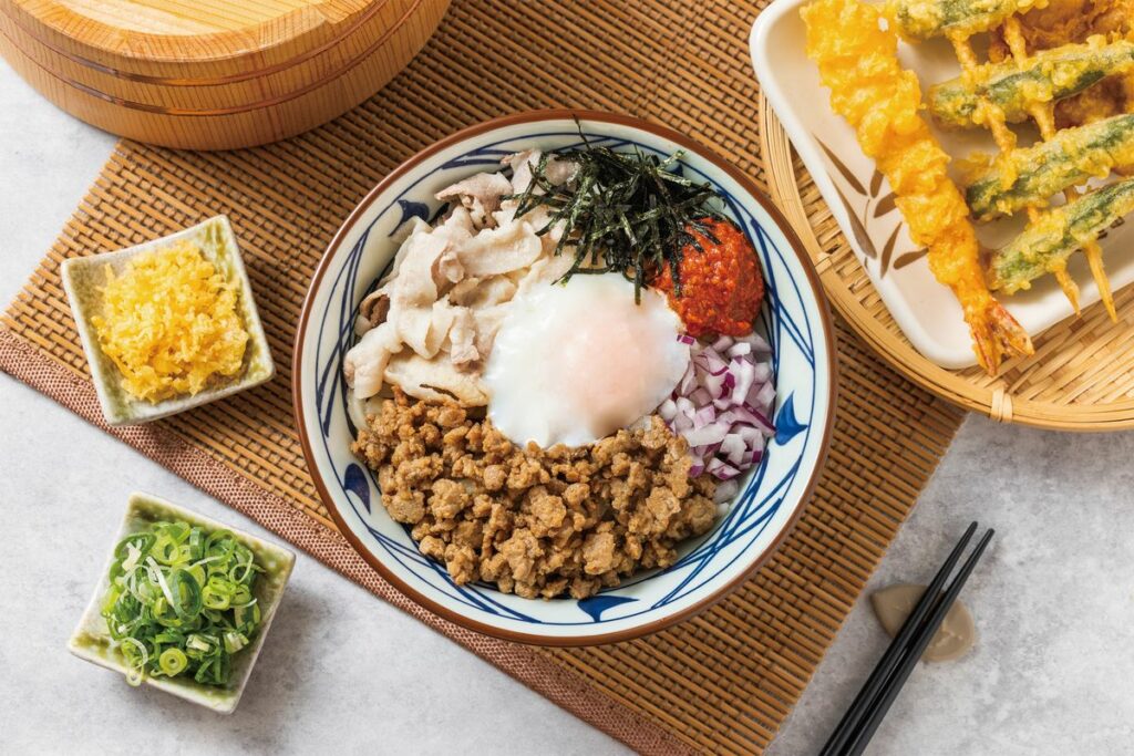 「豐盛豬肉辣拌烏龍麵」軟嫩豬腹肉和日式香料豬絞肉，雙重肉感超飽足，鮮辣交融是初夏開胃的必點美食！中碗 139元，附海帶芽湯。