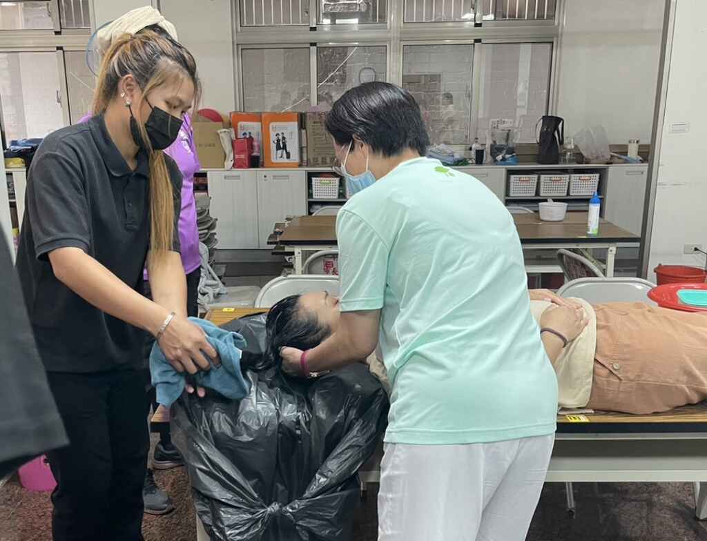 ▲軒晨練習為長者床上洗頭。(中彰投分署提供)
