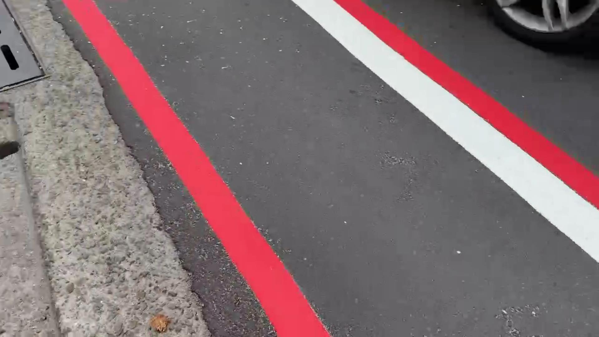 ▲花壇鄉花壇街等路段，最近出現紅、白、紅三條線並行的道路標線，員警看了也滿臉「三條線」，直呼「被考倒了」。（記者張溎壕攝）
