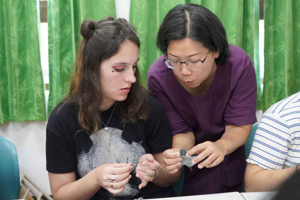 ▲大葉大學華語中心彭涵梅主任(右)教境外學生做香包。(大葉大學提供)