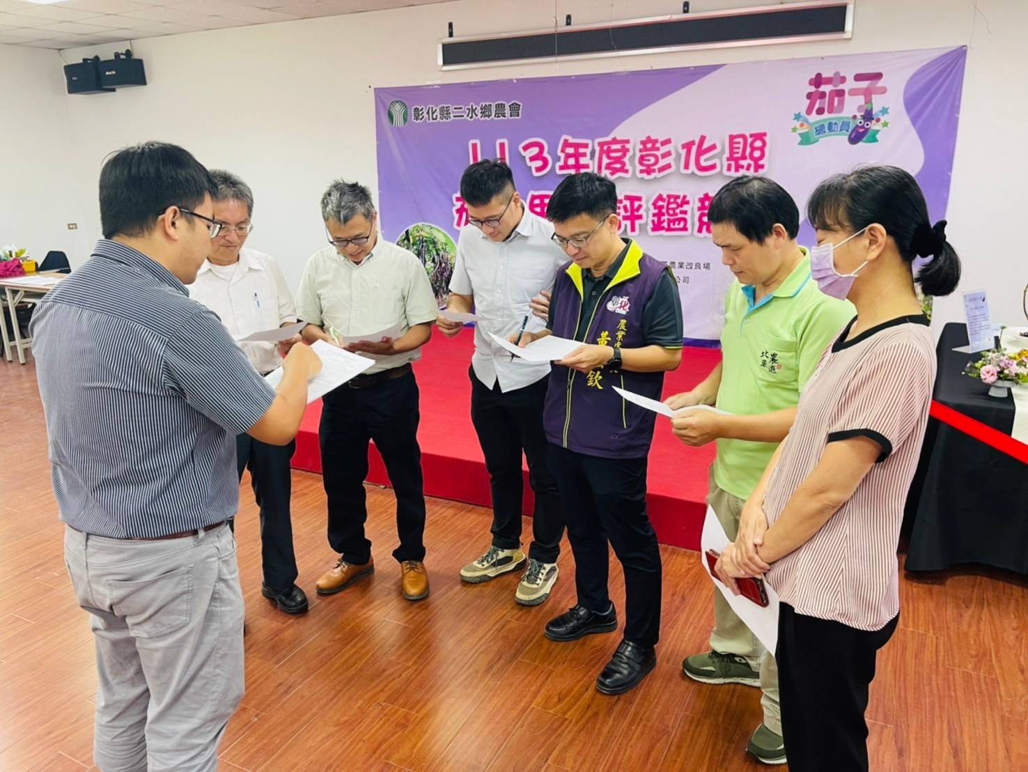 ▲113年度彰化縣茄子果品評鑑競賽在二水鄉農會辦理，評審從茄子果品的長度、色澤、均勻、肉質彈性等項目打分數。（記者張溎壕攝）