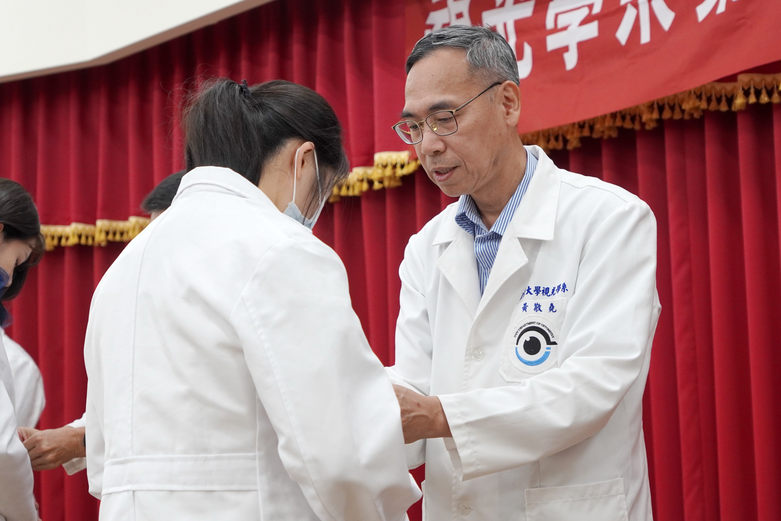 ▲大葉大學視光系老師為學生扣上白袍的第一顆扣子。（記者張溎壕攝）